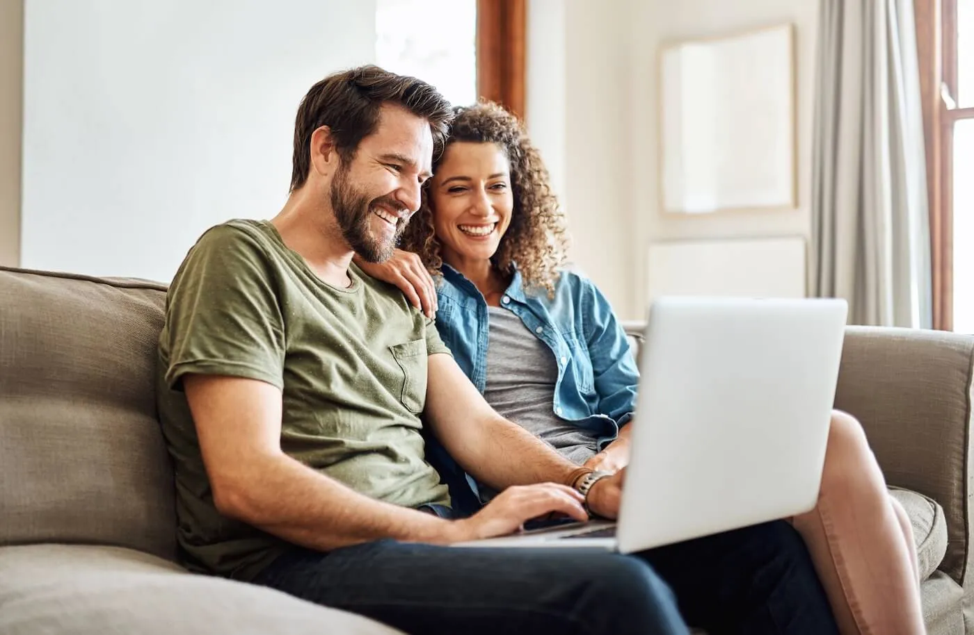 Happy young couple using laptop at home
